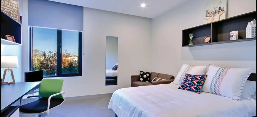 Bed desk couch pillows window bedroom at Scape Berkeley in Melbourne Student Accommodation