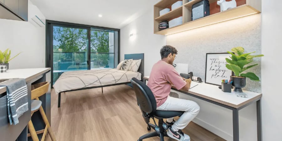 Bed desk shelving with student studying Bedroom study area at UniLodge Melbourne Flagstaff in Melbourne Student Accommodation
