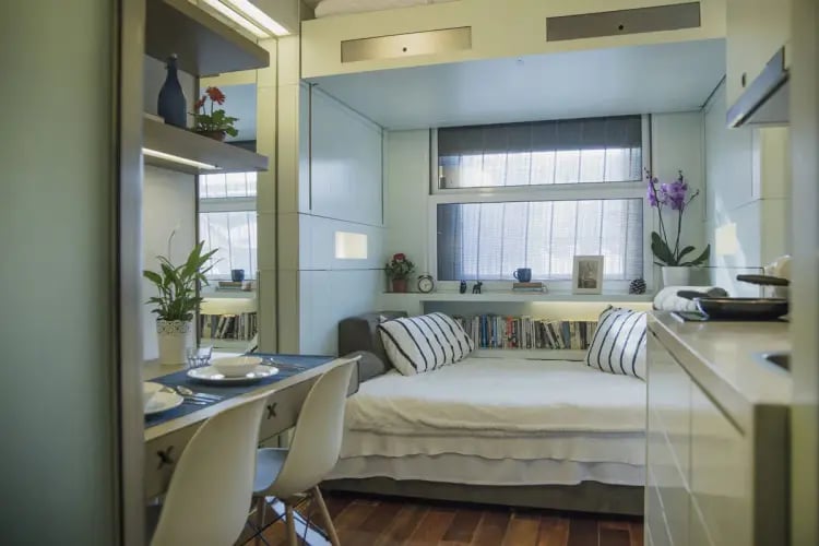 Bed dining table white chairs and plants studio apartment at The Stay Club - Camden in London Student Accommodation