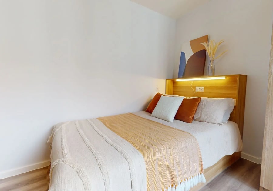 Bed with pillows throws and artwork Bedroom at iQ Sterling Court in London Student Accommodation