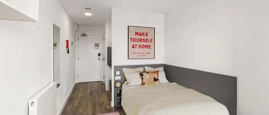 Bed with artwork and hallway with mirror bedroom at Chapter Highbury II in London Student Accommodation