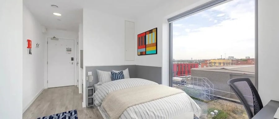 Bed with striped bedding artwork desk chair bedroom at Chapter Highbury II in London Student Accommodation