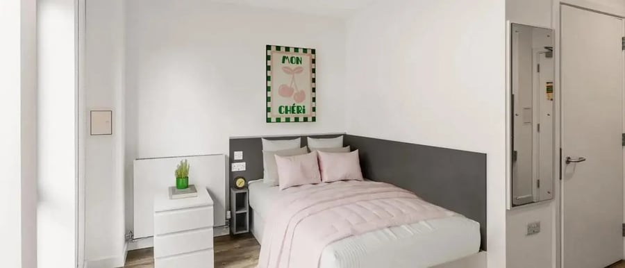 Bed with pink bedding nightstand and art bedroom at Chapter Highbury II in London Student Accommodation