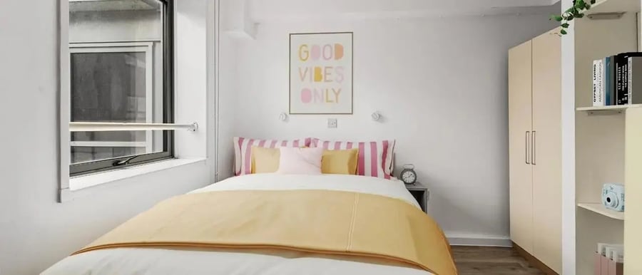 Bed with yellow blanket and pillows wardrobe bedroom at Chapter Islington in London Student Accommodation
