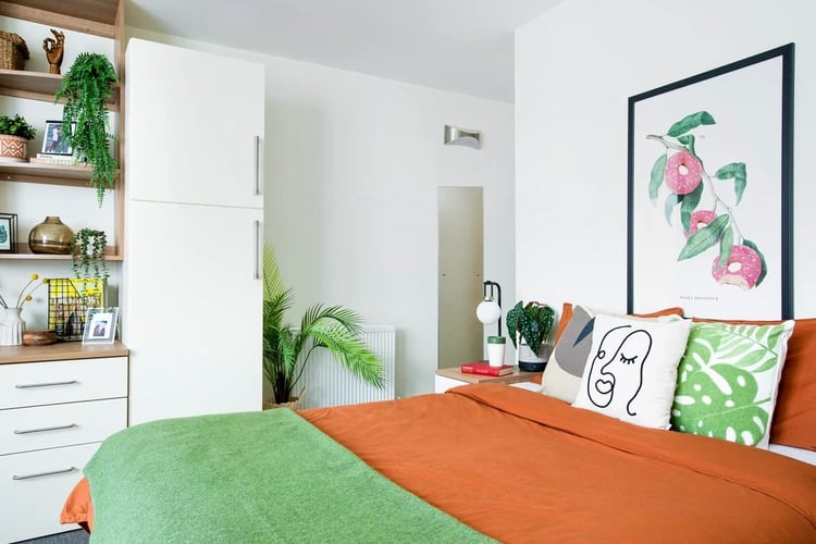 Bed with orange and green bedding pillows bedroom at Moonraker Point in London Student Accommodation
