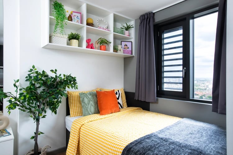 Bed with yellow checkered bedding grey throw bedroom at Hayloft Point in London Student Accommodation