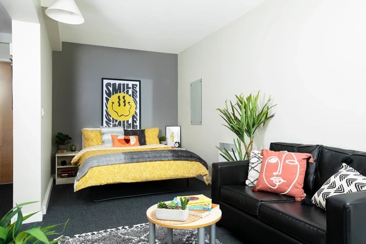 Bed with yellow bedding black sofa and coffee table bedroom at Rahere Court in London Student Accommodation