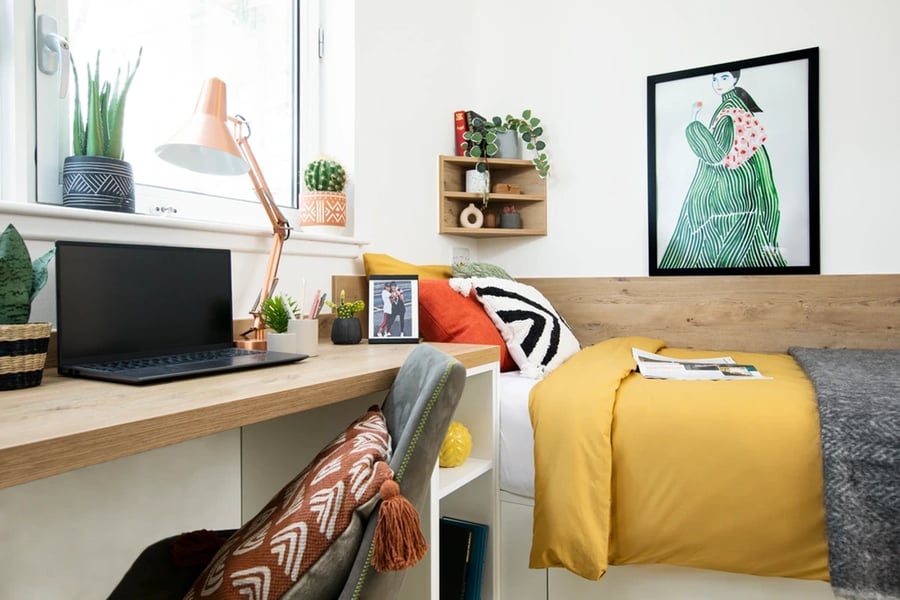 Desk with laptop bed with yellow bedding bedroom at Walmsley Studios in London Student Accommodation