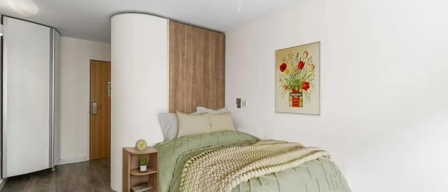 Bed with green duvet and art bedroom at Chapter Islington in London Student Accommodation