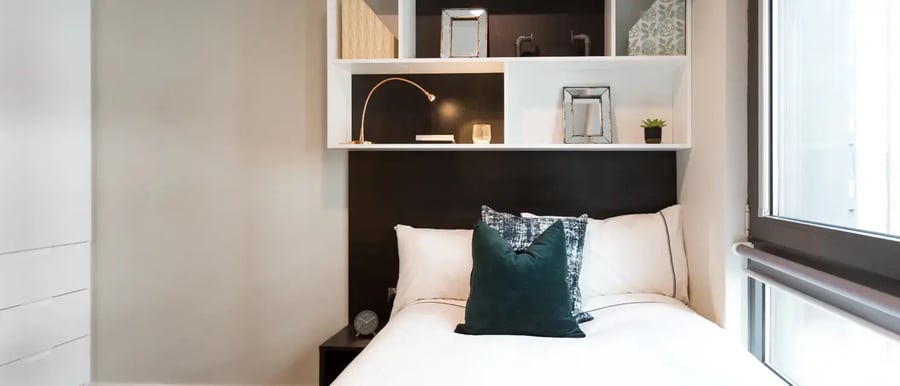 Bed with pillows shelves and lamp bedroom at Chapter Old Street in London Student Accommodation