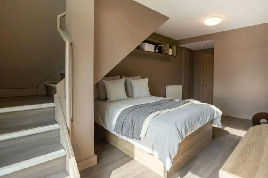 Bed with pillows and blanket stairs and shelf Bedroom at West Gate in Exeter Student Accommodation