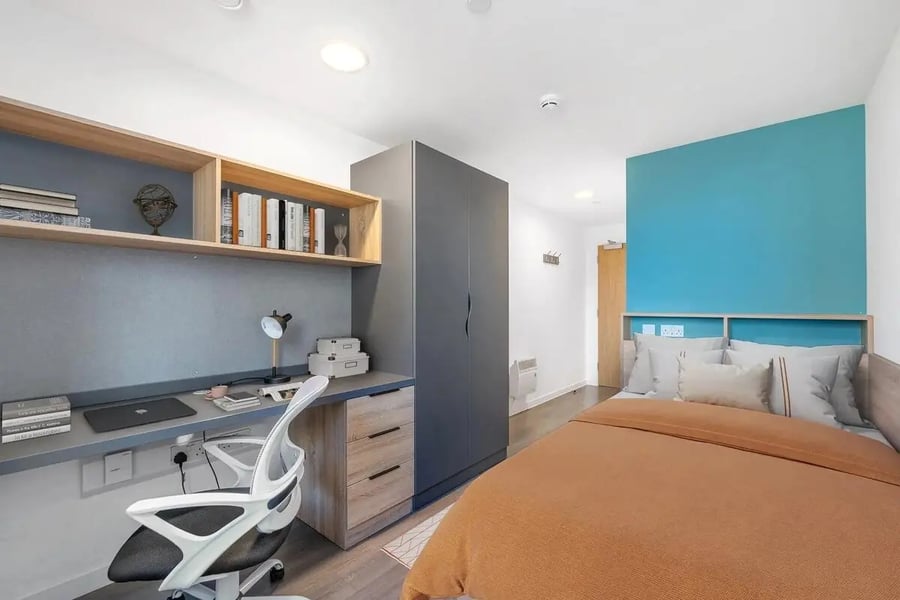 Desk shelves wardrobe bed and pillows bedroom at Canvas Walthamstow in London Student Accommodation