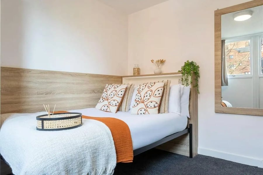 Bed with patterned pillows and white throw Bedroom at dwell 121 Princess Street in Manchester Student Accommodation