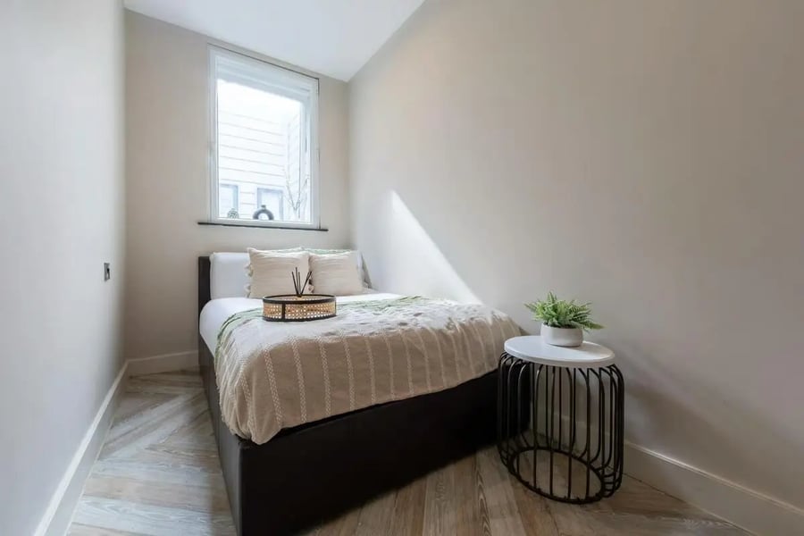 Bed with pillows side table and plant bedroom at dwell 121 Princess Street in Manchester Student Accommodation