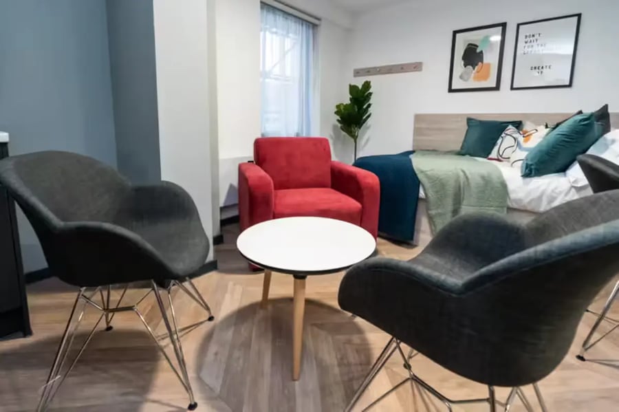 Three chairs table bed and plant living room at Steelworks in Sheffield Student Accommodation