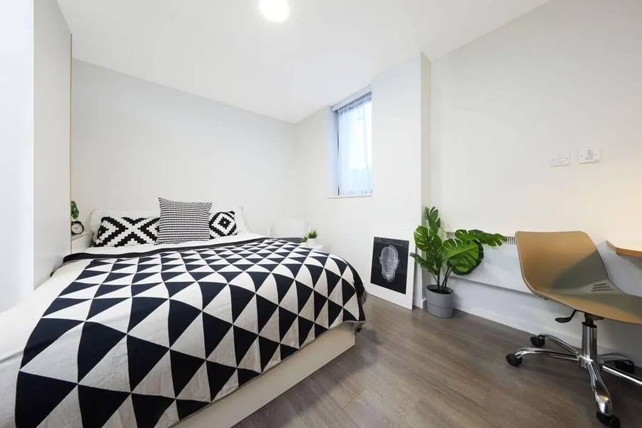 Bed with geometric throw black white pillows desk chair bedroom at Collegiate Merlin Heights in Leicester Student Accommodation