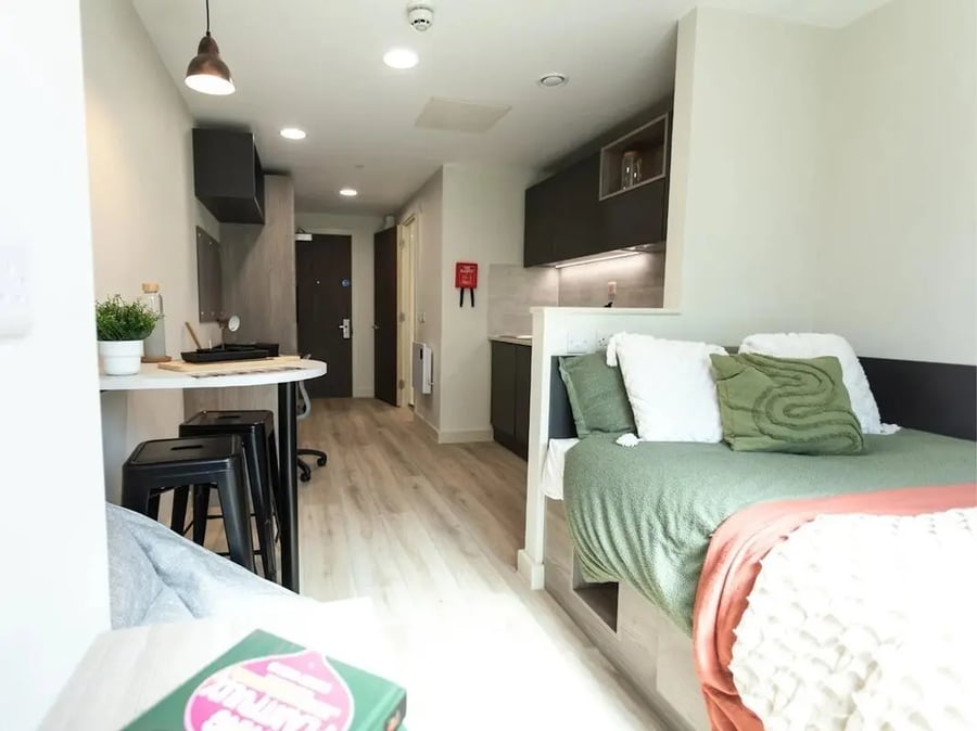 Bed with green bedding desk kitchen and stools bedroom at Stanley Studios - Portsmouth in Portsmouth Student Accommodation
