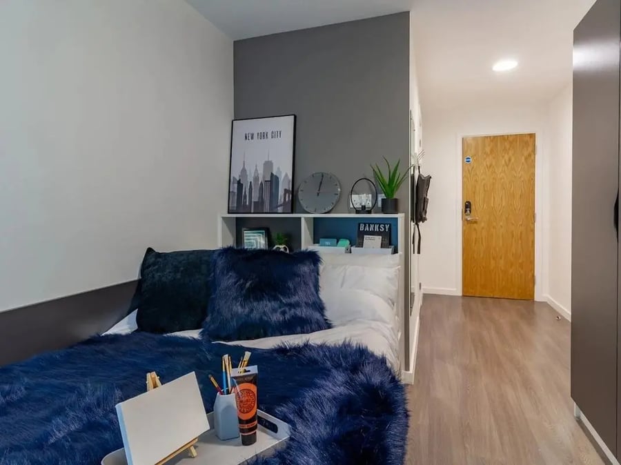 Bed with navy fur throw New York poster study area at Pavilion Court London in London Student Accommodation