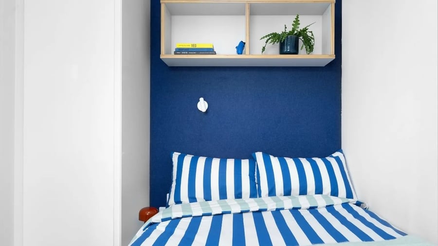 Blue bed with striped bedding and shelf bedroom at Scape Bloomsbury in London Student Accommodation
