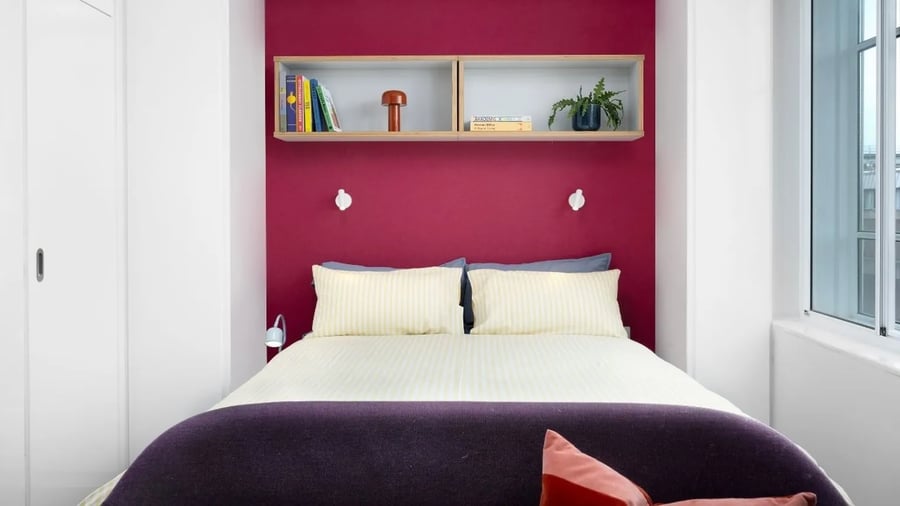 Bed with purple headboard white bedding shelves bedroom at Scape Bloomsbury in London Student Accommodation