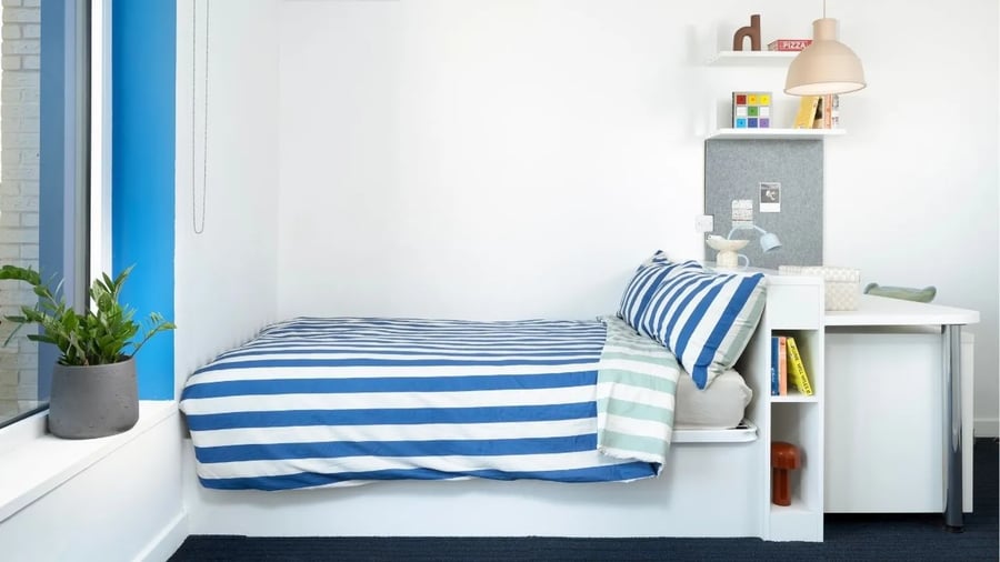 Striped bed desk shelves plant bedroom at Scape Canada Water in London Student Accommodation