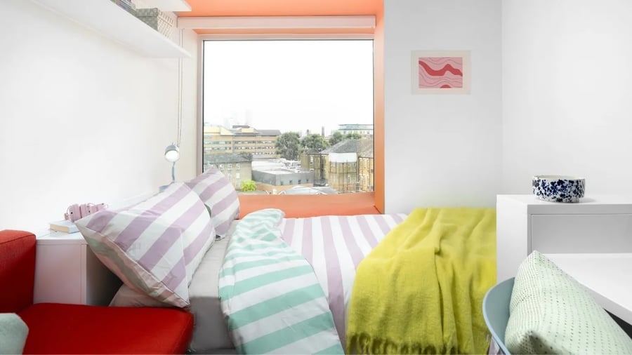 Bed with striped bedding red sofa yellow throw Bedroom at Scape Mile End in London Student Accommodation