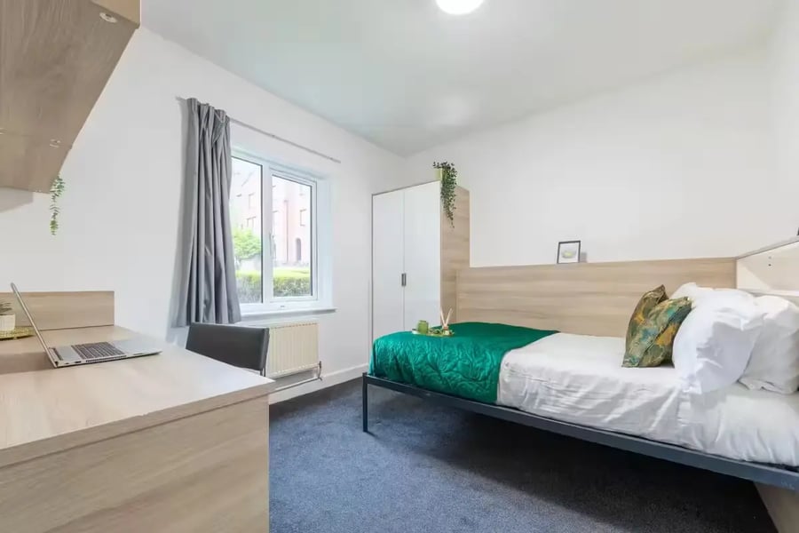 Desk laptop wardrobe bed with green bedding bedroom at dwell Cathedral Campus in Liverpool Student Accommodation