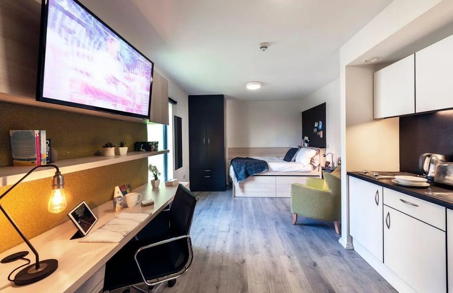 Bed desk chair TV and kitchen area studio at The Lyra in London Student Accommodation