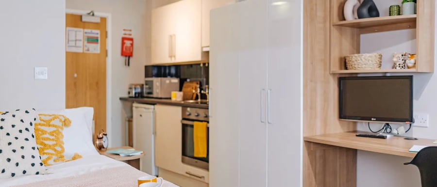 Bed with pillows kitchenette study area and television at Chapter South Bank in London Student Accommodation