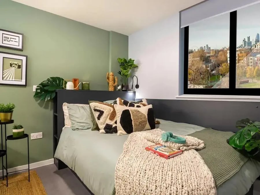 Bed with patterned pillows blanket and city view bedroom at Element Bermondsey in London Student Accommodation