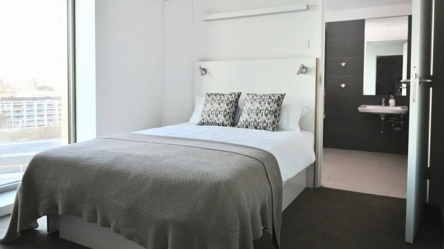 Bed with grey blanket and patterned pillows bedroom at Victoria Hall Kings Cross in London Student Accommodation