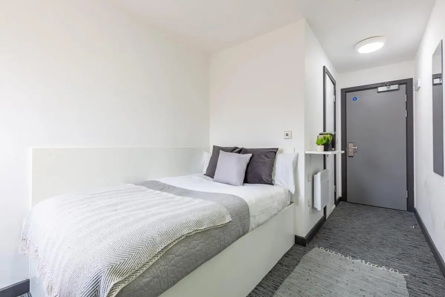Bed pillows radiator door carpeted floor bedroom at Glassworks - Liverpool in Liverpool Student Accommodation