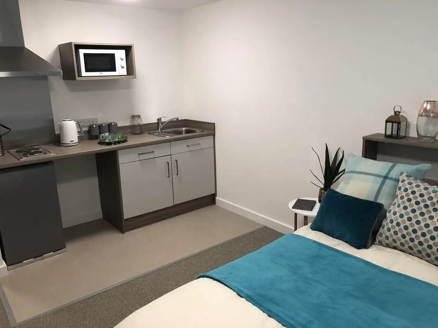 Kitchenette with microwave sink bed and pillows bedroom at Q Studios in Stoke-On-Trent Student Accommodation