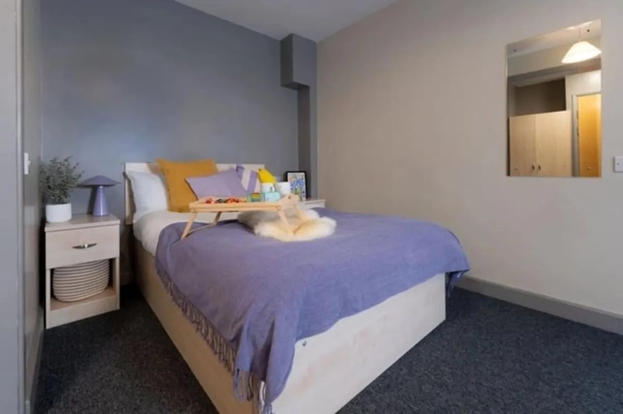 Bed with purple blanket tray pillows side table bedroom at The Heights in Birmingham Student Accommodation