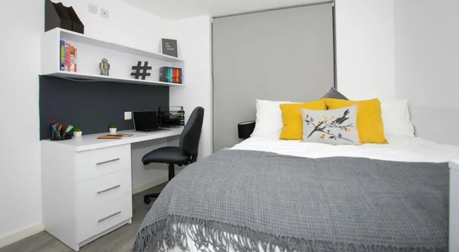 Desk with laptop and bed with pillows bedroom at The Cube Ealing in London Student Accommodation