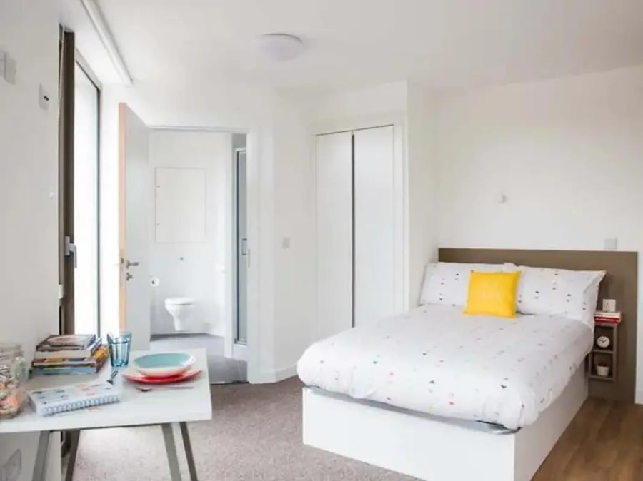 Bed with yellow cushion and toilet visible bedroom at Felda House in Wembley Student Accommodation