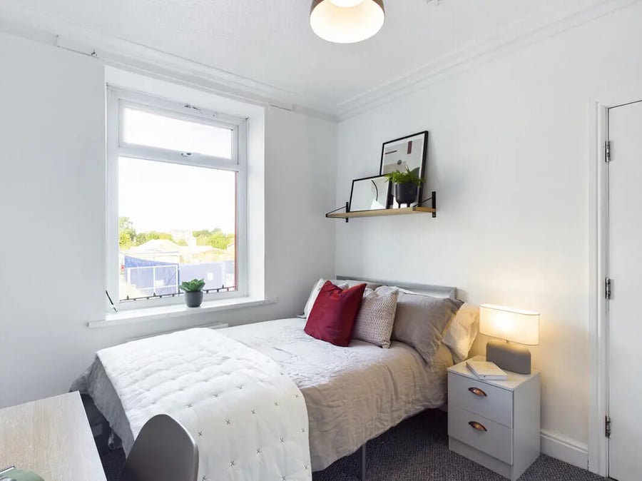 Bed with red pillows bedside table bedroom at 6 Bedroom House at 75A, West Parade in Lincoln Student Accommodation