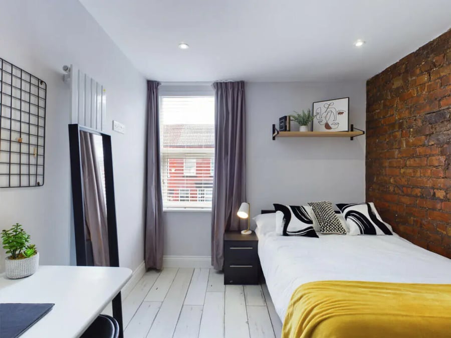 Bed mirror desk plant and brick wall bedroom at 8 Bedroom House at 211, Molyneux Road in Liverpool Student Accommodation