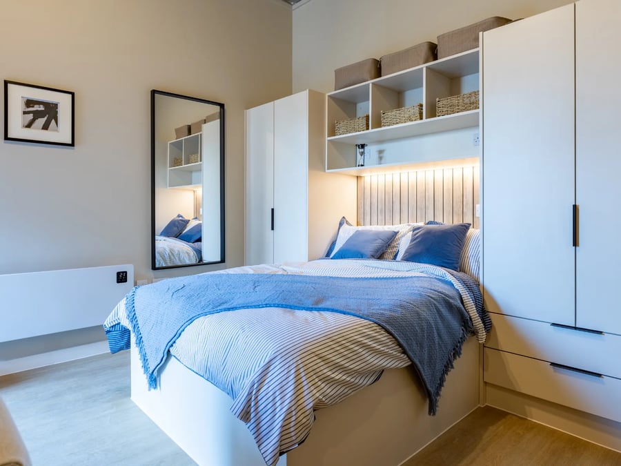 Bed with blue blankets and pillows beside wardrobe bedroom at Fitz and Knox in Cardiff Student Accommodation