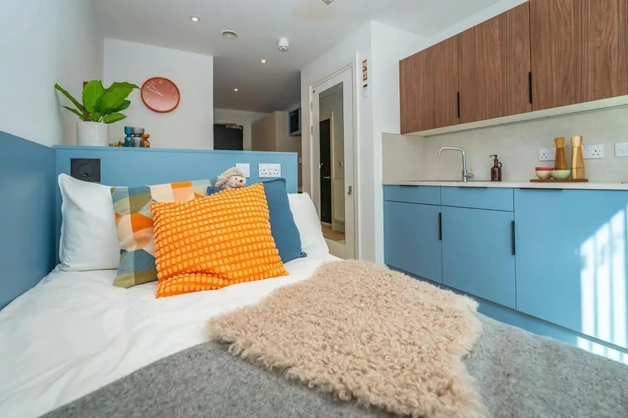 Bed with pillows and kitchen unit at The Propeller Quarter in Bristol Student Accommodation