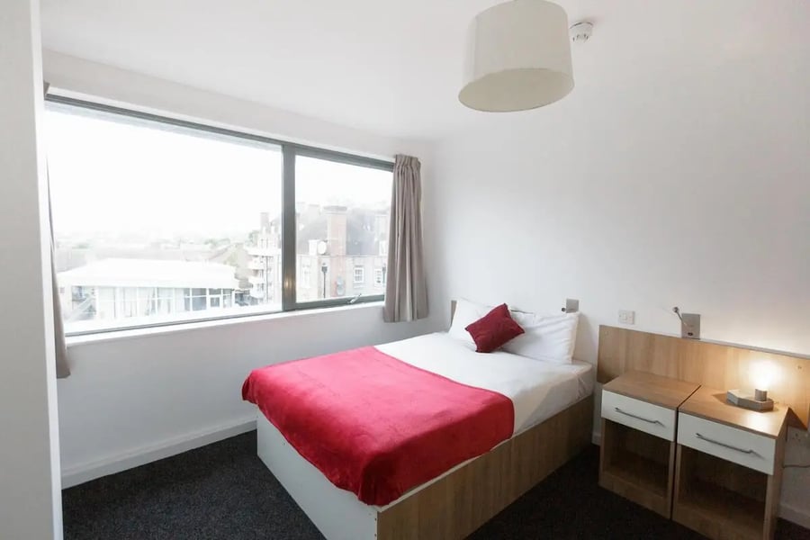 Bed with red throw bedside tables and window bedroom at AXO Camden in London Student Accommodation