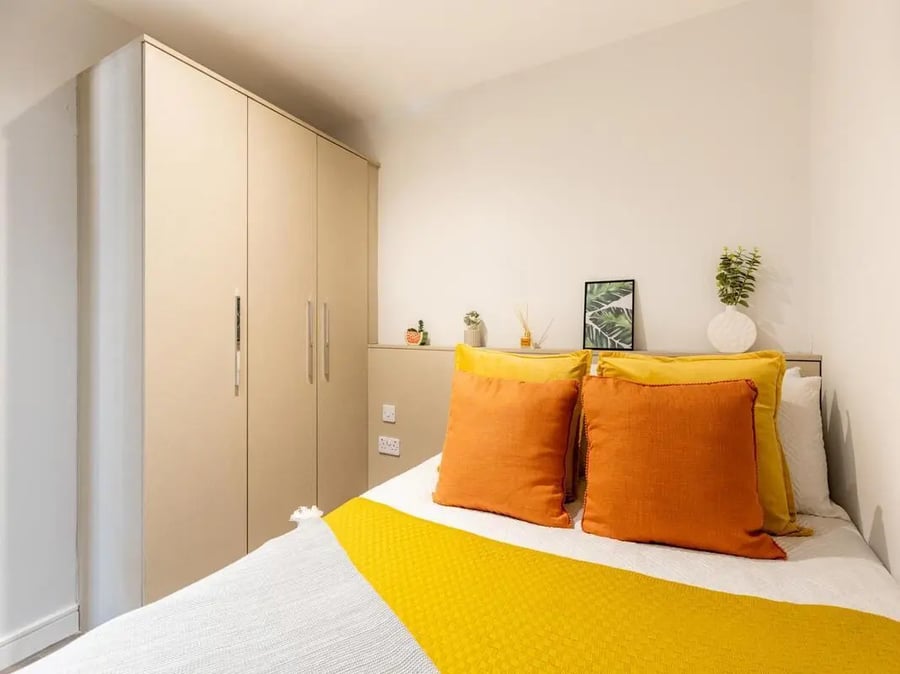 Closet bed with orange pillows and yellow throw bedroom at Redvers Tower in Sheffield Student Accommodation