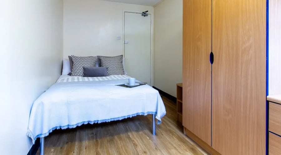 Bed with patterned pillows wardrobe and tray bedroom at Ben Russell Court in Leicester Student Accommodation