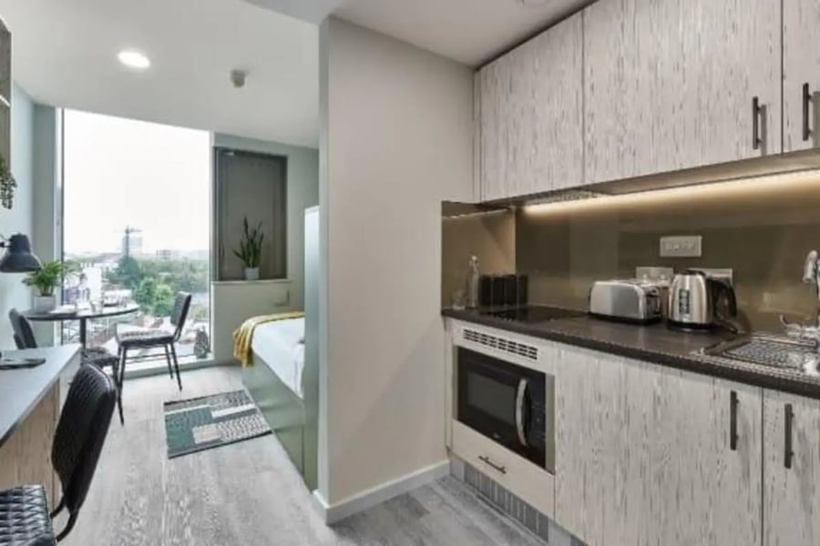 Studio apartment with bed desk kitchen and chairs studio at Flora Building - Hoxton in London Student Accommodation