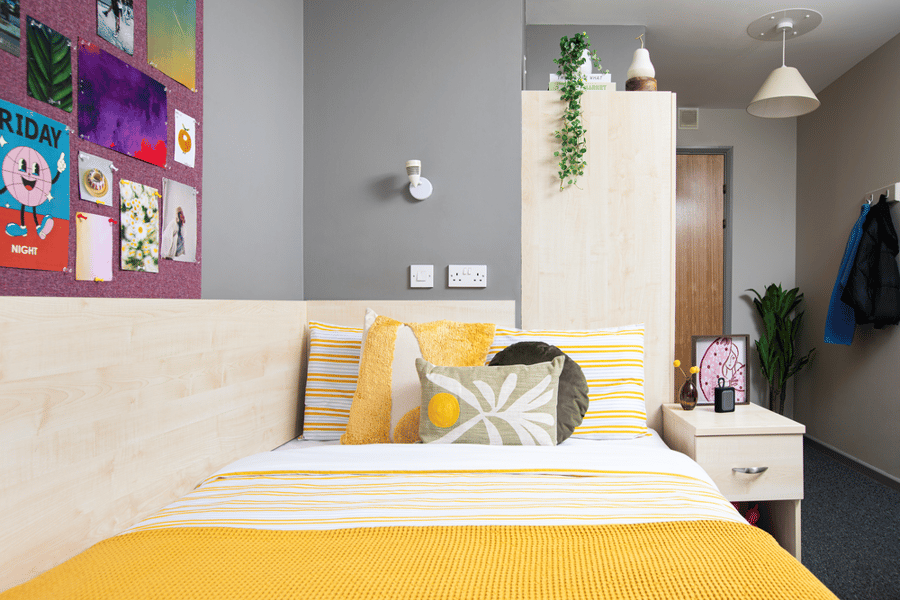 Bed with yellow bedding and decorative pillows bedroom at Newarke Point in Leicester Student Accommodation