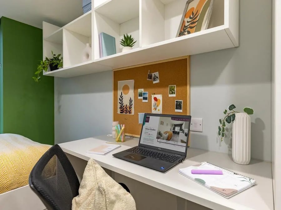 Desk with laptop corkboard shelves and bedding study area at Venue Studios in London Student Accommodation