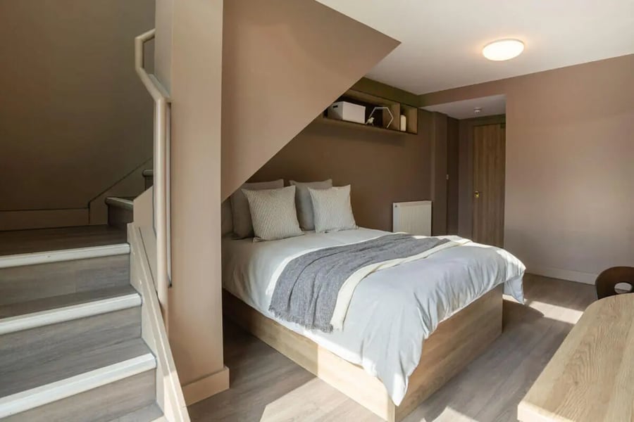 Bed with pillows and blanket stairs and shelf bedroom at West Gate in Exeter Student Accommodation