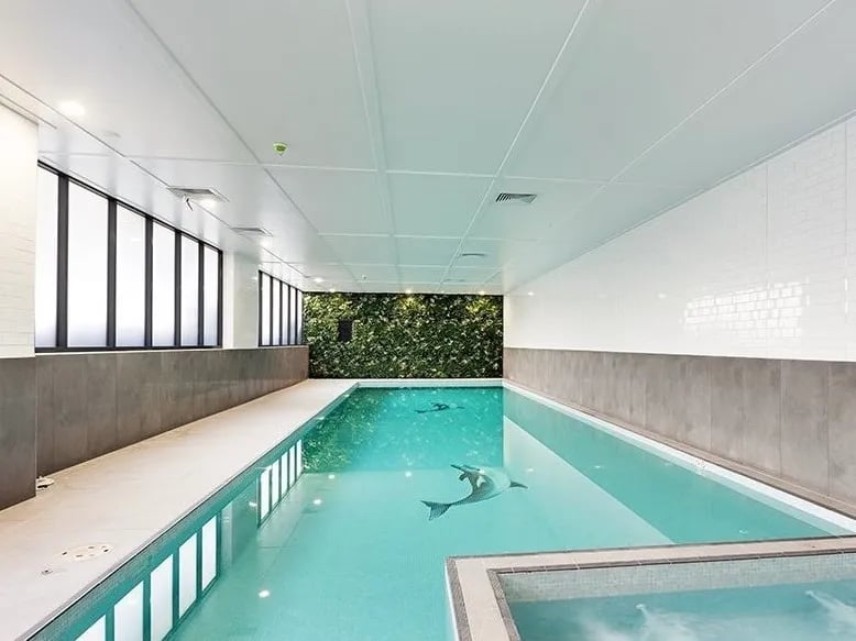 Indoor swimming pool with green wall art and dolphin tiles Swimming Pool at Belong Mascot in Sydney Student Accommodation
