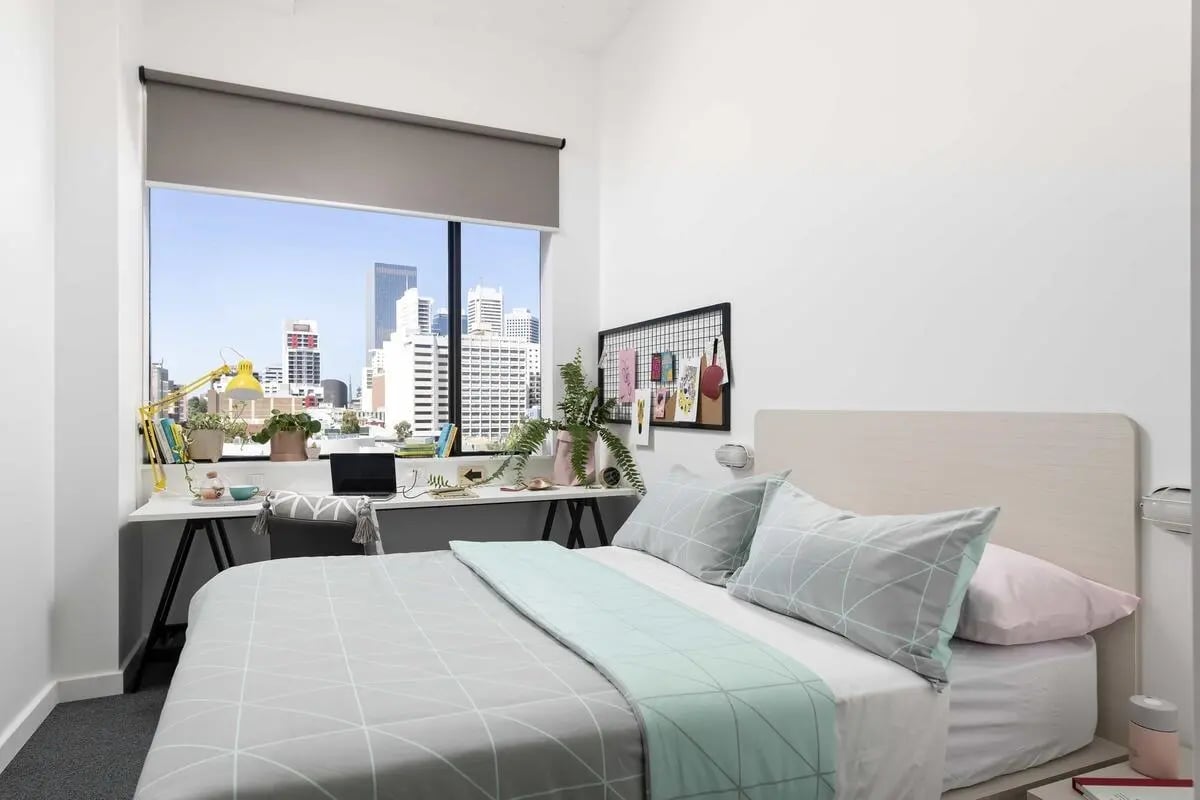 Bed desk plants window cityscape bedroom at Campus Perth in Perth Student Accommodation