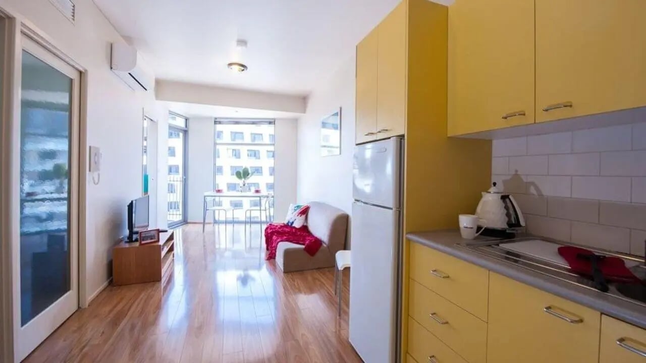 Yellow cabinets sofa tv and dining table apartment living room at Student Living - 570 Swanston in Melbourne Student Accommodation